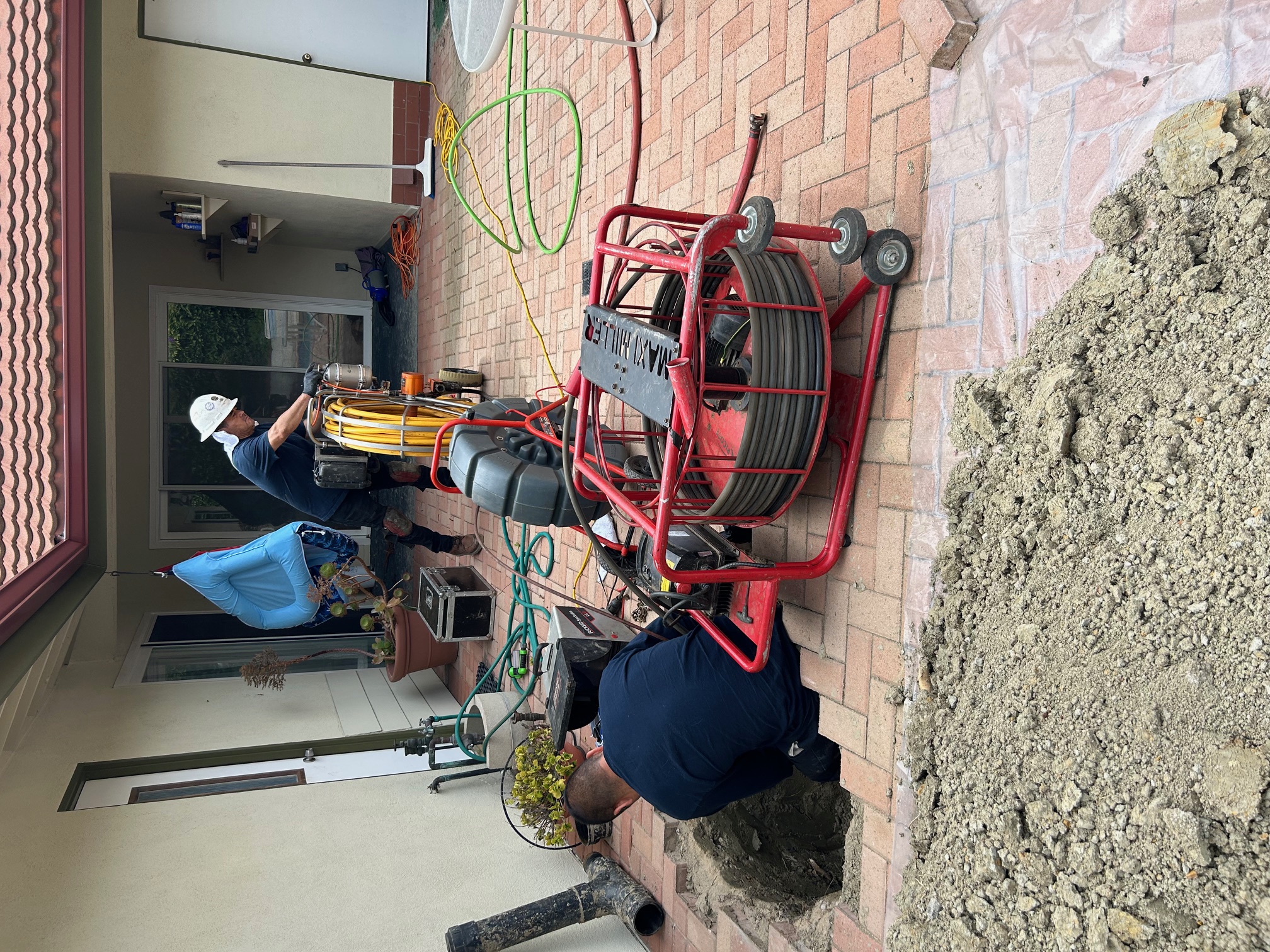 Plumbing team trenching back patio sewer line